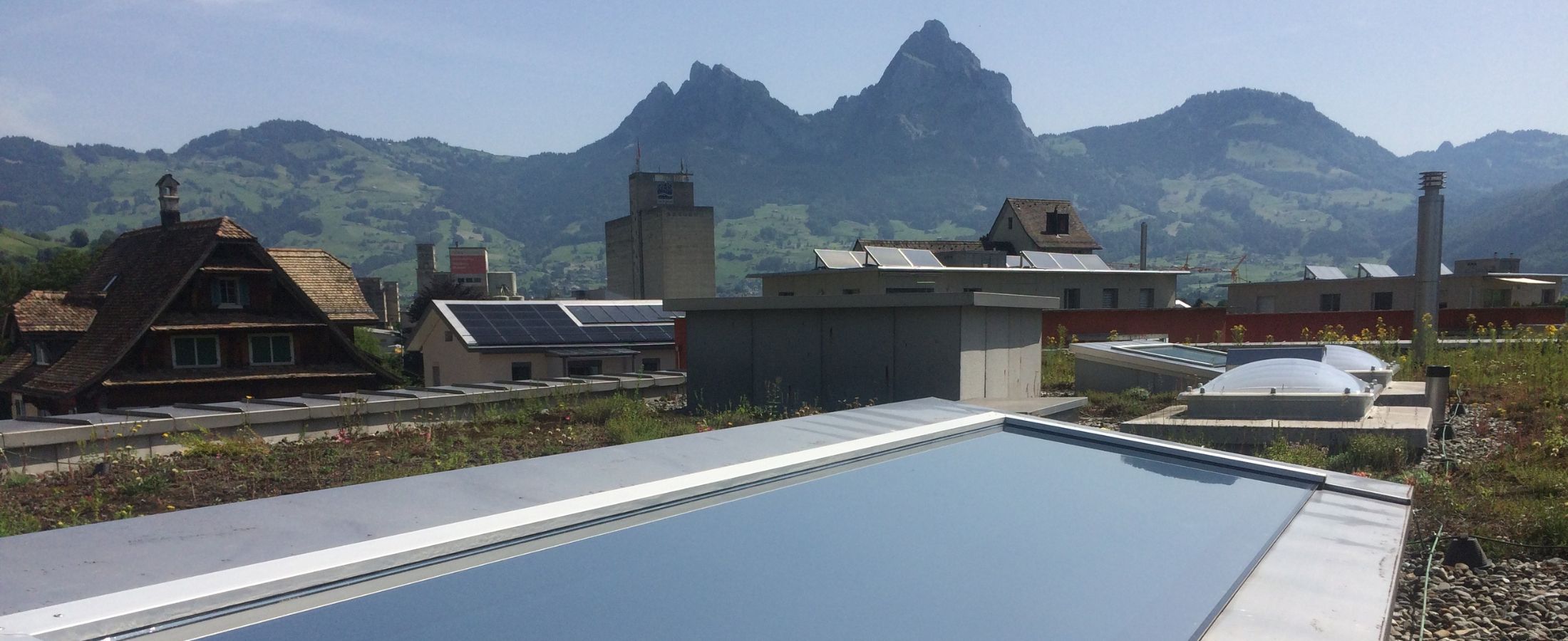 Grossflächiges Dachfenster mit silberner Sonnenschutzfolie und Berglandschaft im Hintergrund.